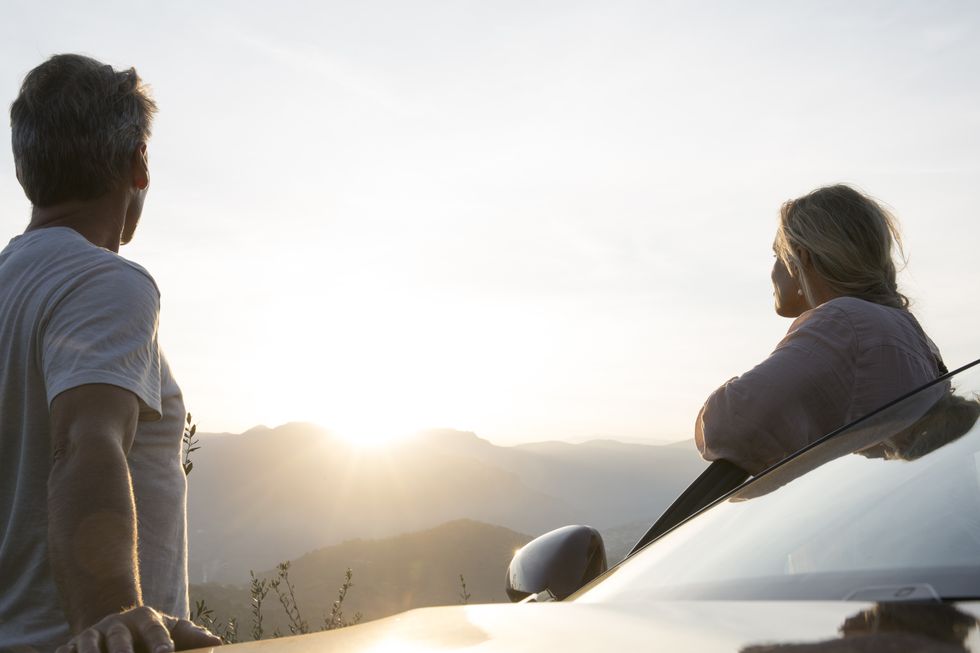 couple-stand-by-car-door-look-to-sunrise-hills-royalty-free-image-1652236368.jpg